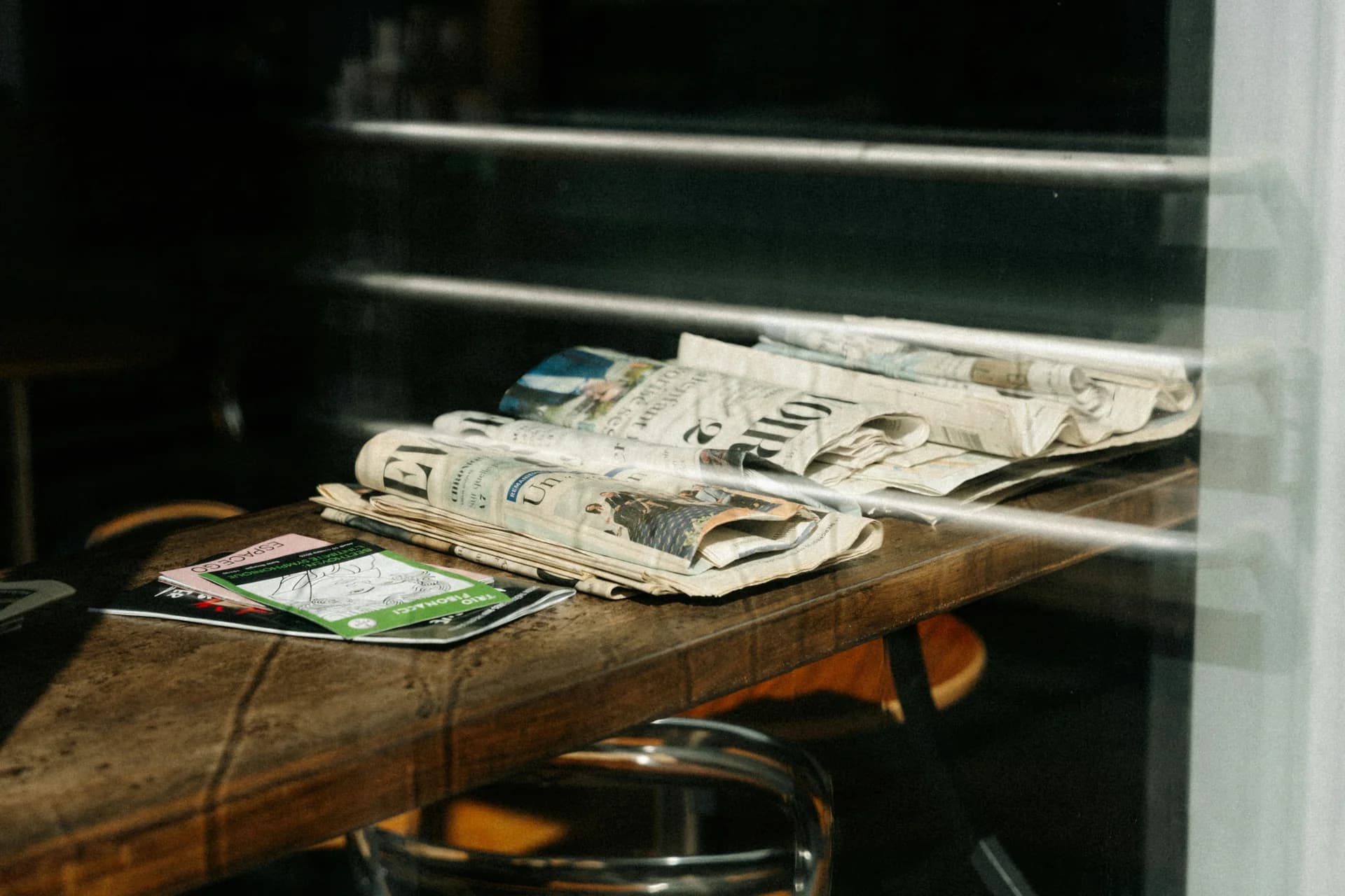 Stack of newspapers and magazines on a wooden table — launch season editorial